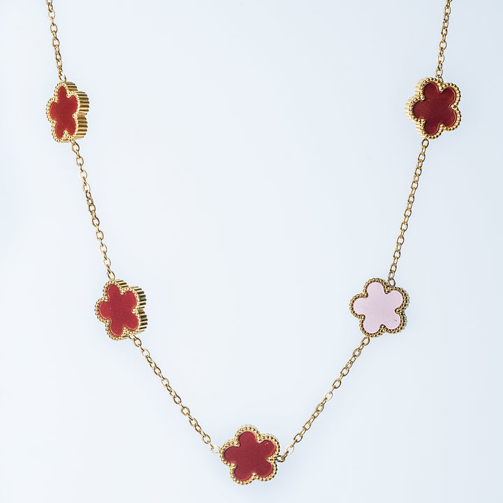 Gold Fiore necklace featuring alternating red and pink flower-shaped links on a white background