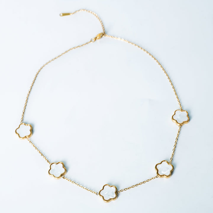 Gold Fiore necklace featuring white mother-of-pearl flower-shaped links on a white background