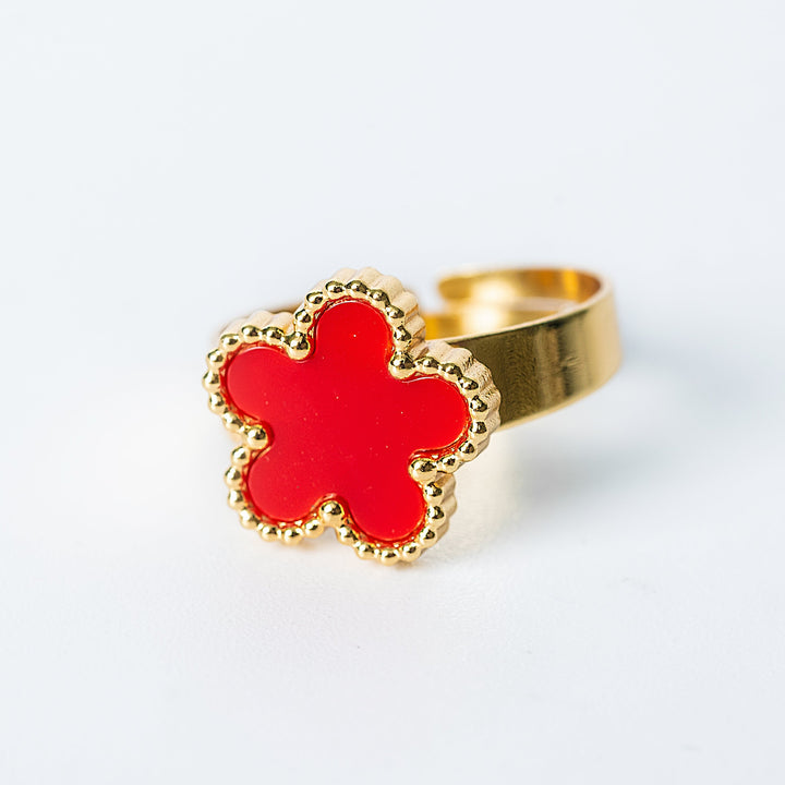 Gold Fiore ring featuring a bright red flower-shaped enamel centerpiece on a white background