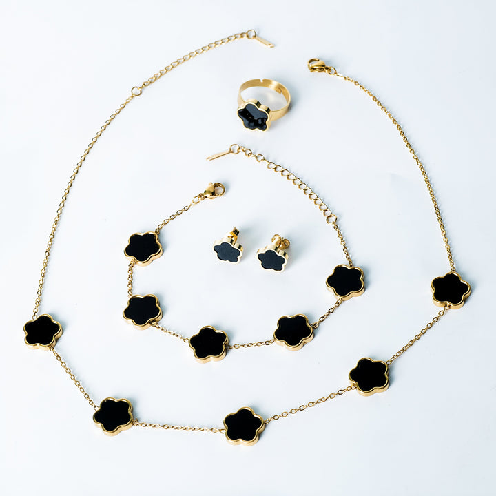 Fiore Set in gold featuring a matching black flower necklace, bracelet, earrings, and ring displayed on a white background
