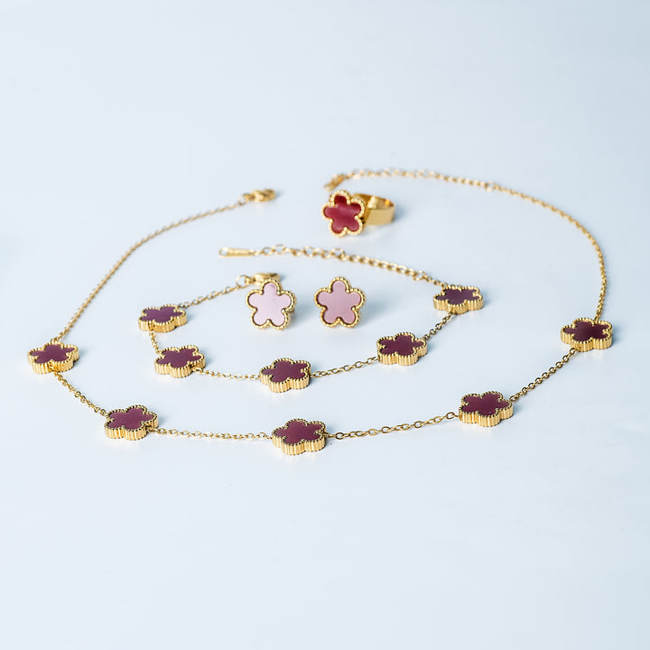 Fiore Set in gold featuring a matching dark red and pink flower necklace, bracelet, earrings, and ring displayed on a white background