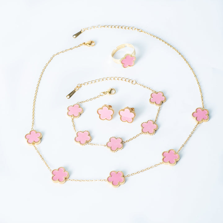 Fiore Set in gold featuring a matching pink flower necklace, bracelet, earrings, and ring displayed on a white background
