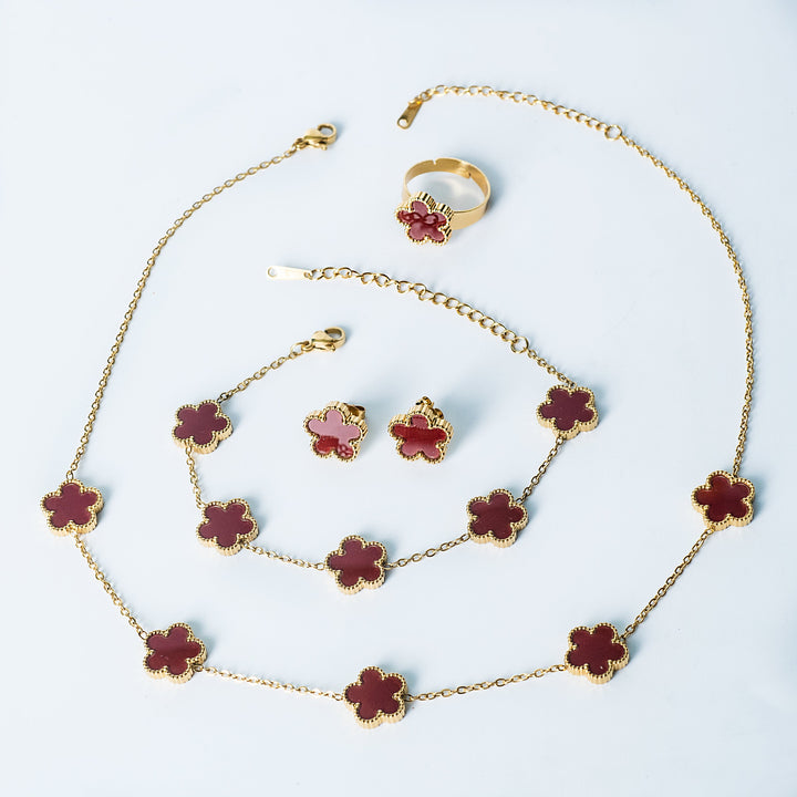 Fiore Set in gold featuring a matching red flower necklace, bracelet, earrings, and ring displayed on a white background