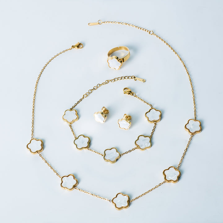Fiore Set in gold featuring a matching white mother-of-pearl flower necklace, bracelet, earrings, and ring displayed on a white background