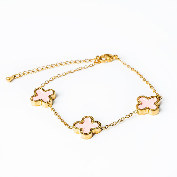 A yellow gold stainless steel bracelet with pink enamel accents in the shape of flowers.