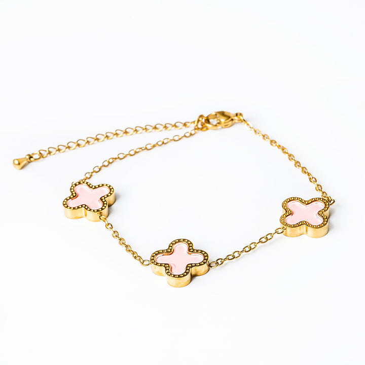 A yellow gold stainless steel bracelet with pink enamel accents in the shape of flowers.