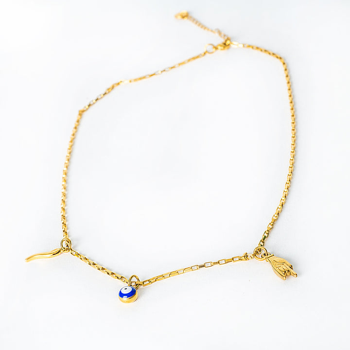 Aa wide view of Xorti necklace with a blue evil eye charm and a hand charm on a white background