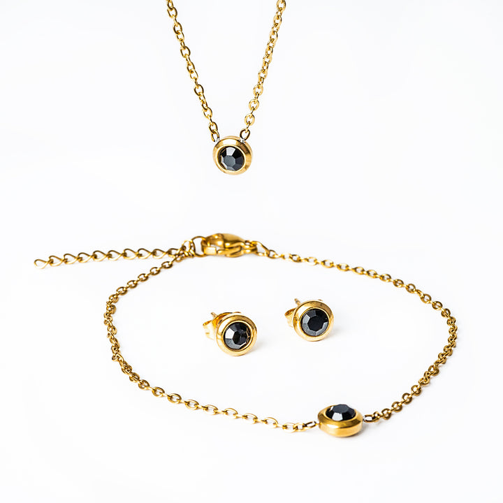 A close up view of Gabriella Gold set with black stones standing in the center of the image against a white background 