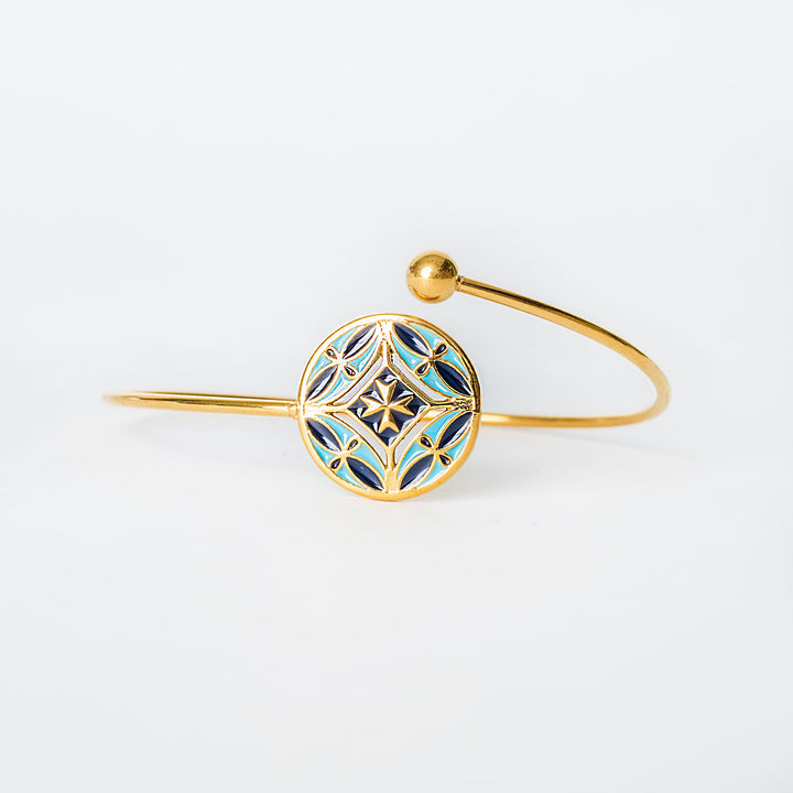 Gold Malta bracelet with a geometric blue design on a white background