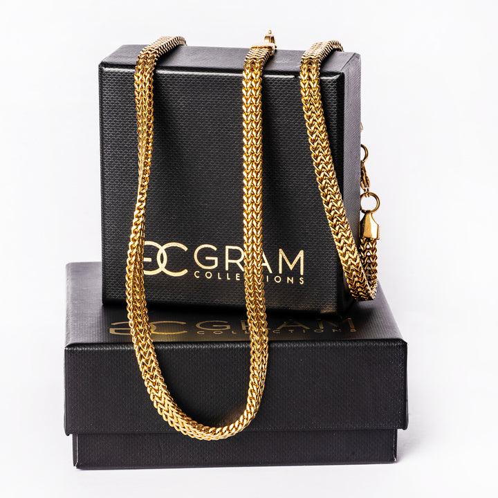 A gold plated sienna necklace and bracelet standing in the center of the image against a white background, placed on their box. 