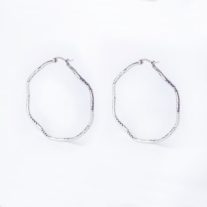 A pair of silver-colored stainless steel Grace hoop earrings on a white background