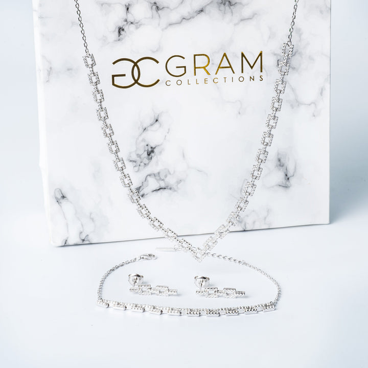 Gram Collections Alana necklace and its set of bracelet and earrings in front of thier white box. 
