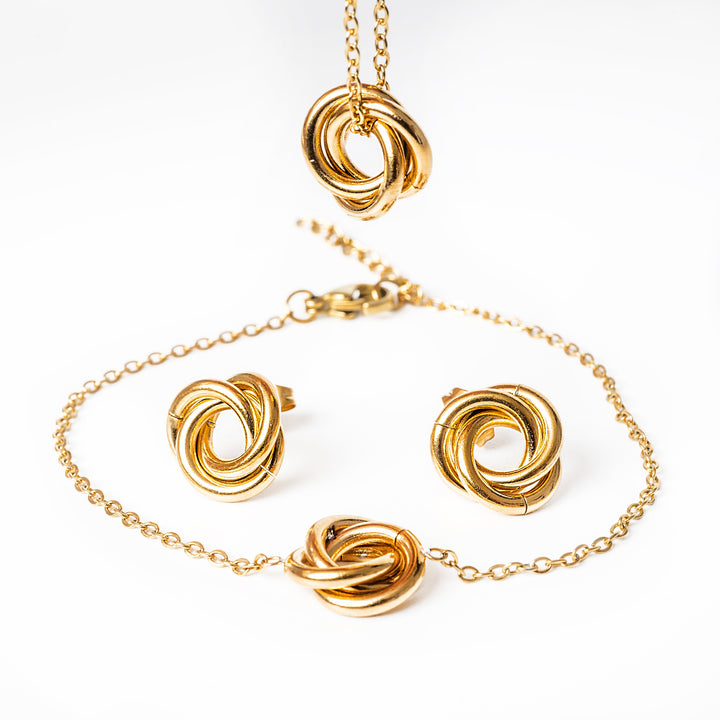 A carment gold earrings standing in the center of the image against a white background. 