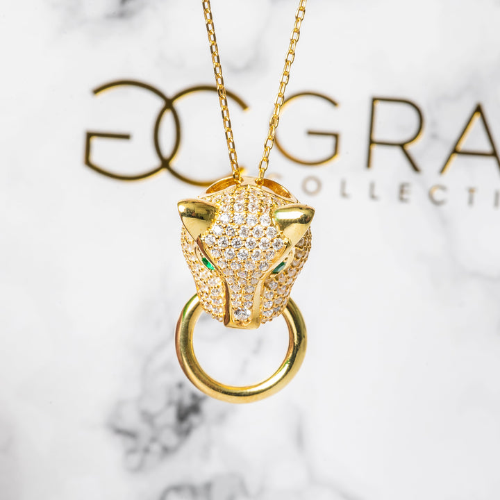 A close up of Chleo Necklace standing in the center of the image against its box standing in the background. 