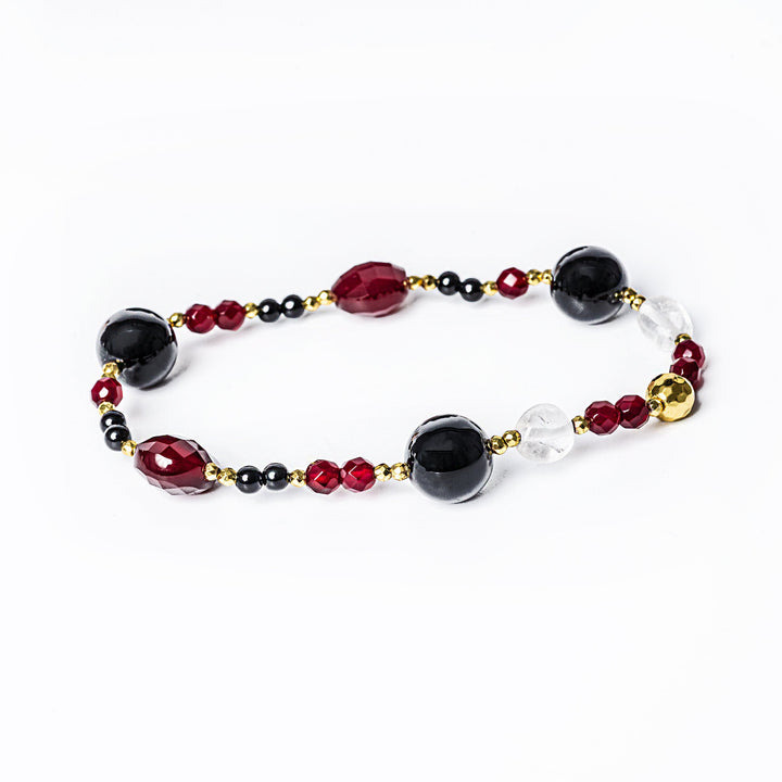 A maroon-colored bracelet with yellow gold plating and natural stone inlays, featuring a combination of red and black beads.