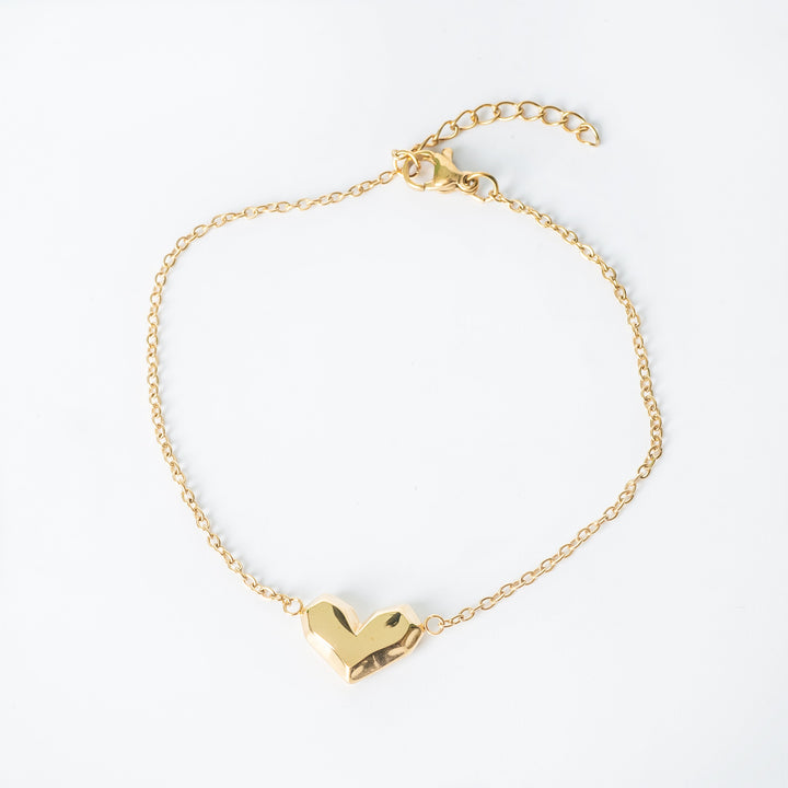 Gold bracelet with a heart shaped pendant shown from a top view