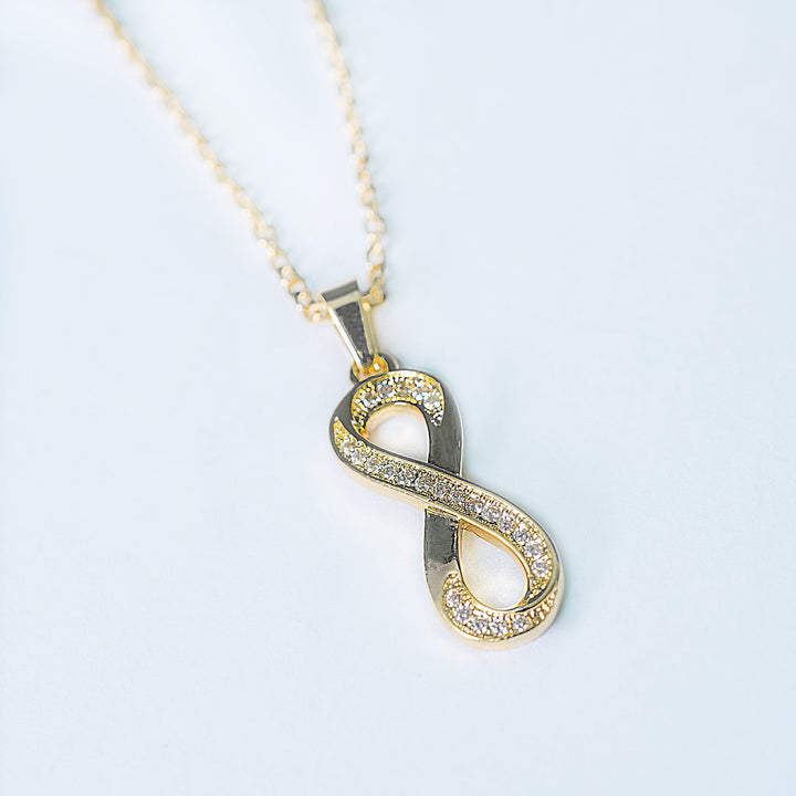 Ina gold necklace with crystal infinity pendant in angled view