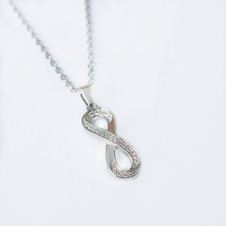 Ina silver necklace with crystal infinity pendant in angled view