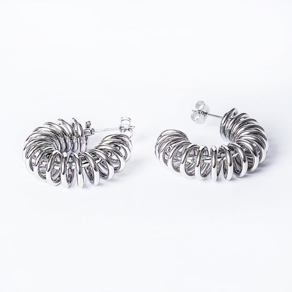 A pair of Ines silver hoop earrings with a gold plated finish on a white background.