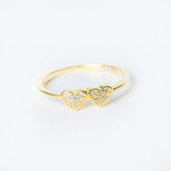 Gold Joanne ring with two small pavé crystal hearts on a white background