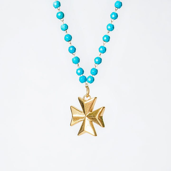 Kahli Necklace with turquoise beads and a gold Maltese cross pendant on a light gray background