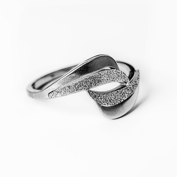 A profile view of Kaycee Silver Ring standing in the center of the image against a white background. 