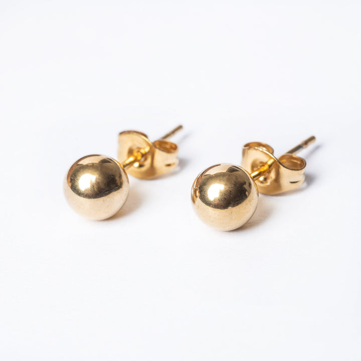 A close up view of Kim Earrings gold colour, standing in the center of the image against a white background. 