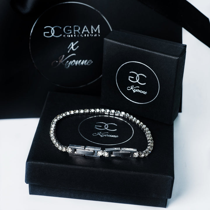 Silver Kyonne diamond tennis bracelet displayed on black branded boxes