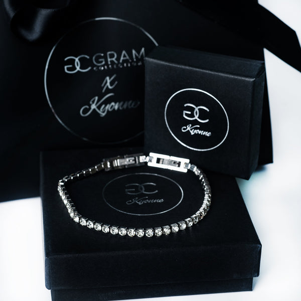 Silver Kyonne diamond tennis bracelet displayed on black branded packaging