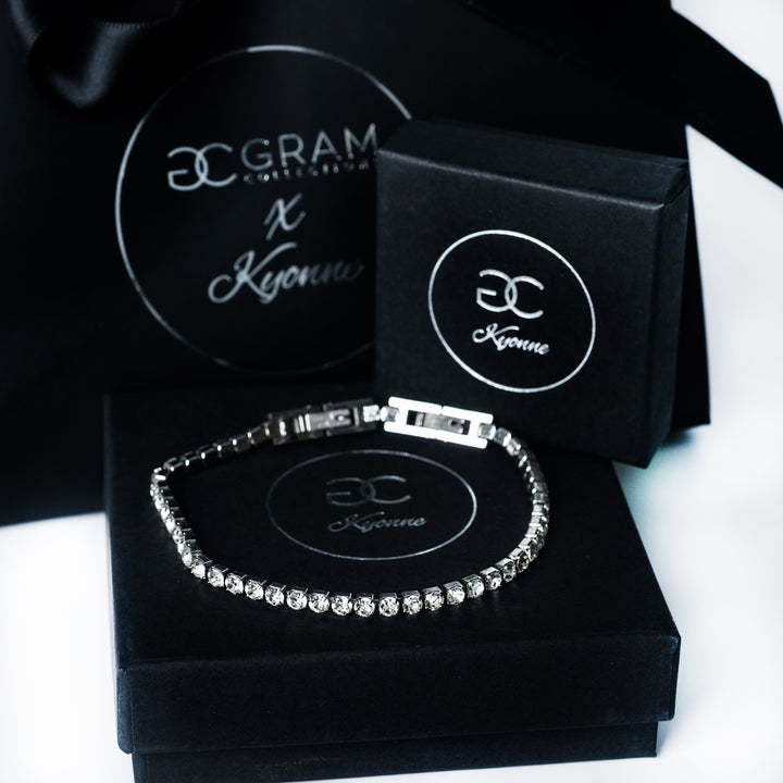 Silver Kyonne diamond tennis bracelet displayed on black branded packaging