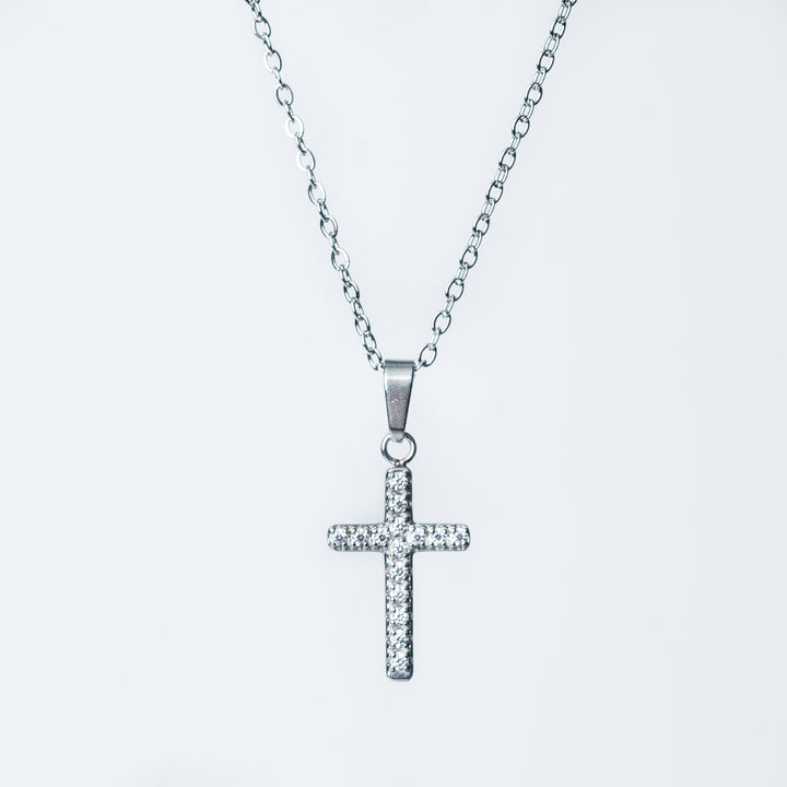 Close up of the silver Kyonne cross necklace with clear diamonds on a white background