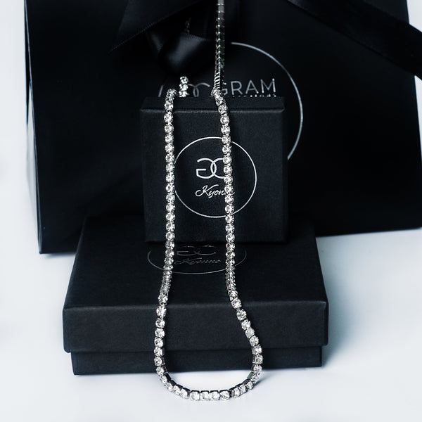 Silver Kyonne diamond tennis necklace displayed on black branded boxes