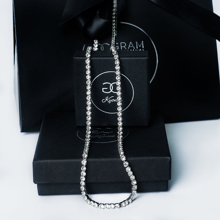Silver Kyonne diamond tennis necklace displayed on black branded boxes