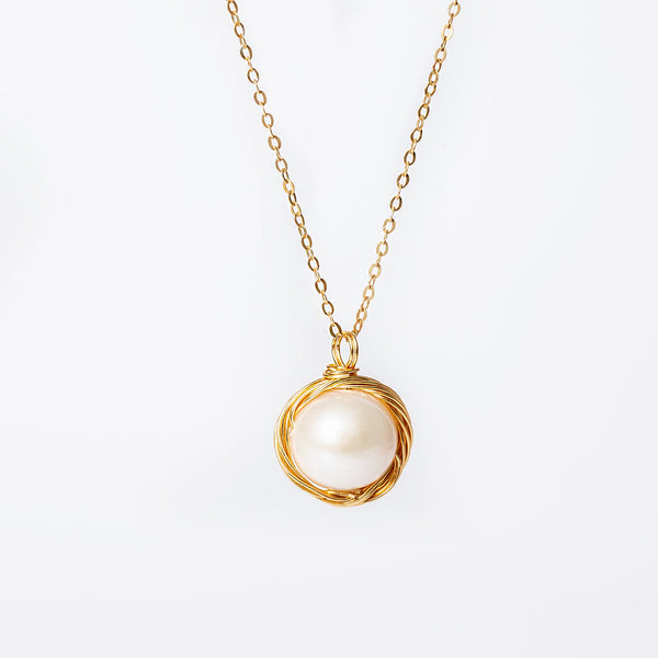 A silver-colored Leah necklace with a yellow gold chain and a single cultured pearl adorned in a yellow gold setting.