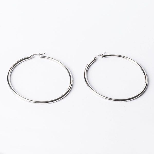 A close up view of Silver earrings standing in the center of the image against a white background. 