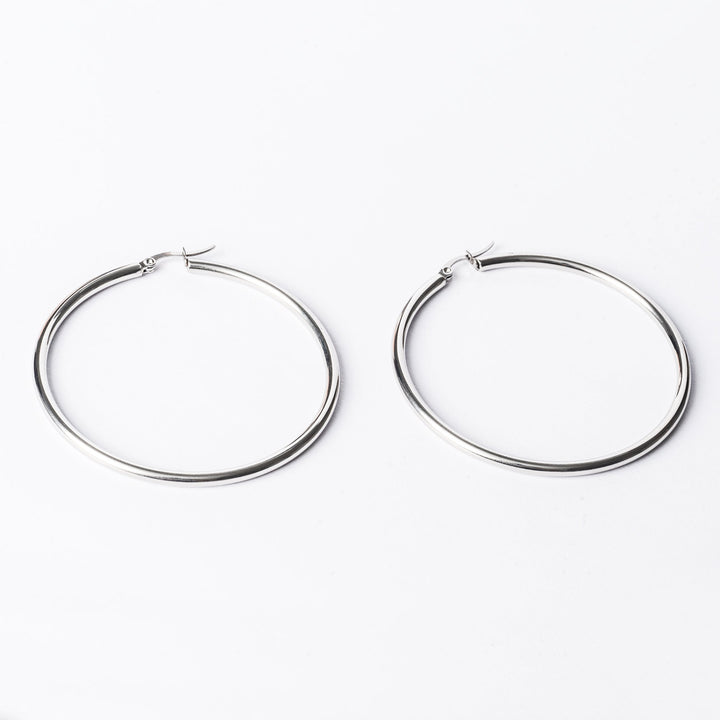 A close up view of Silver earrings standing in the center of the image against a white background. 