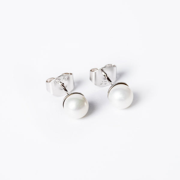 A close up view of lilly earrings standing against a white background. 