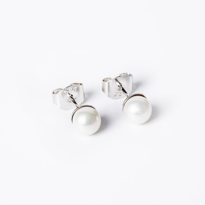 A close up view of lilly earrings standing against a white background. 