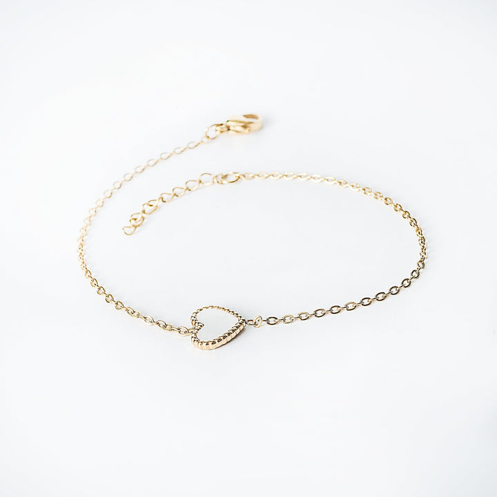 Lisa gold bracelet with an open heart pendant shown from a side angle