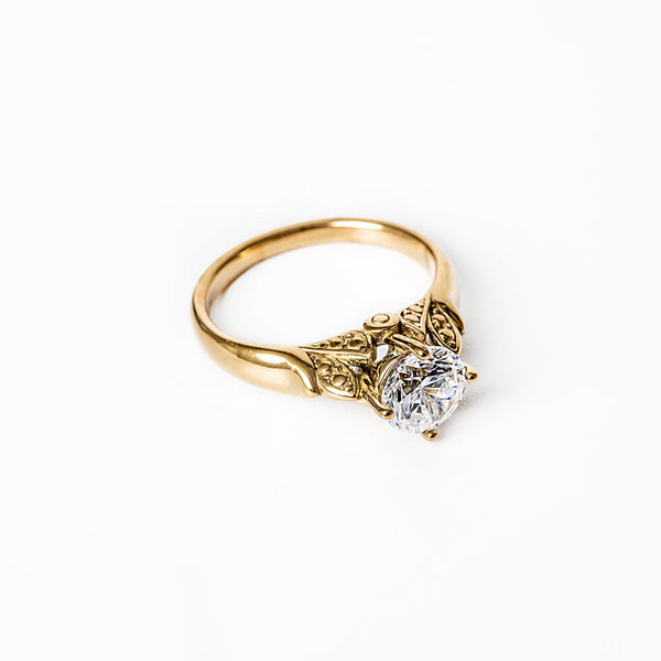 A yellow gold ring with a large central cubic zirconia gemstone, set in a classic six-prong setting, on a white background.