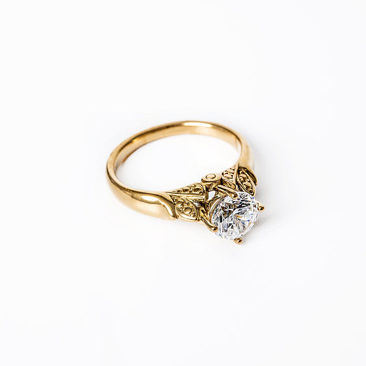 A yellow gold ring with a large central cubic zirconia gemstone, set in a classic six-prong setting, on a white background.