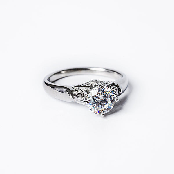 A silver ring featuring a prominent cubic zirconia gemstone in a classic six-prong setting, surrounded by a textured band.