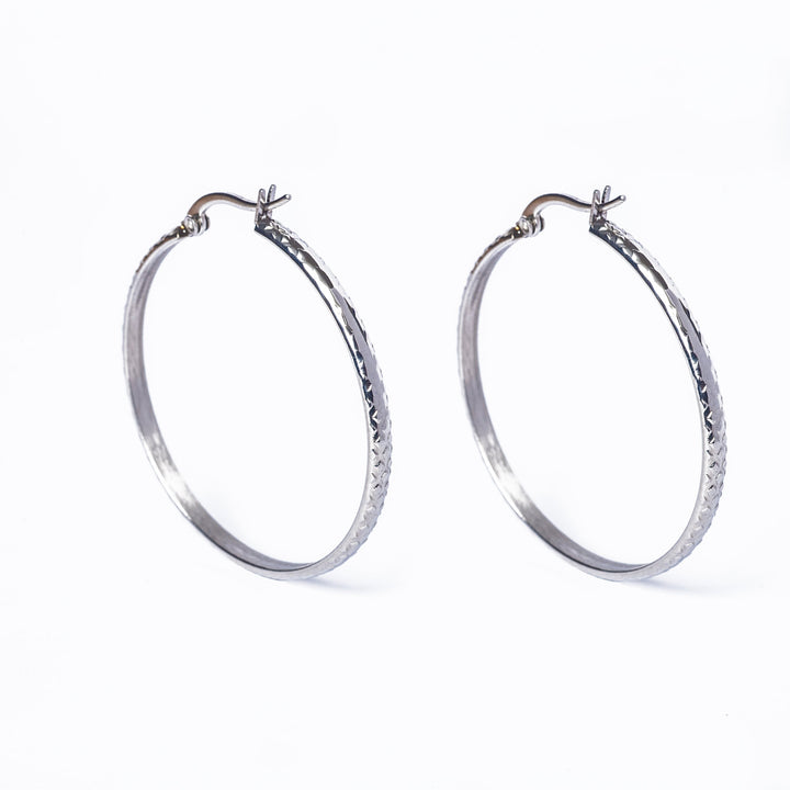 A pair of silver Lucy hoop earrings with a textured design on the hoop surface, displayed against a white background.