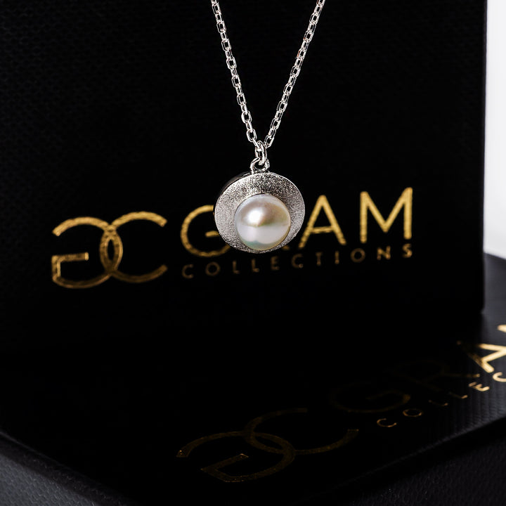 Gram collections Luidsy Necklace standing in the center of the image with its box in the background. 