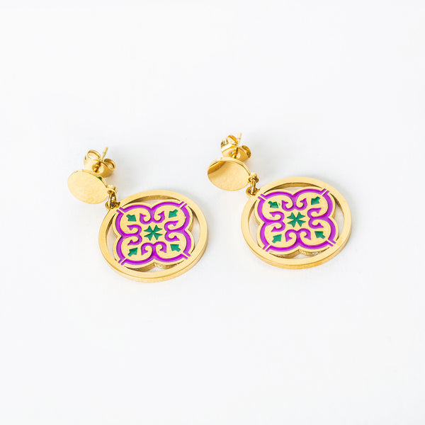 A close up viee of Maduma  earrings with purple and green designs on a white background