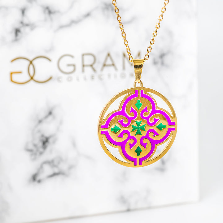 Gold necklace with a colorful pendant on a marble background