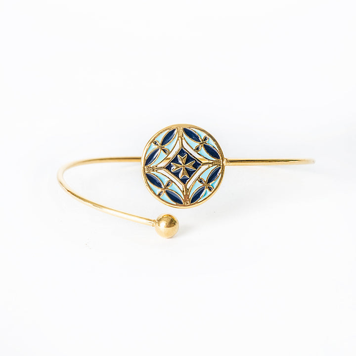 Gold bracelet with blue decorative element on a white background