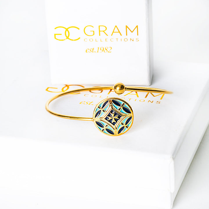 Gold Malta bracelet with blue accents on a white surface, featuring 'OC Gram Collections' branding.