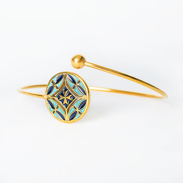 Gold bracelet with blue decorative element on a white background