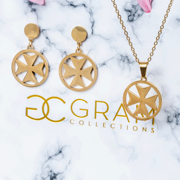 A set of gold-colored stainless steel jewelry including a necklace, a pendant, and a pair of earrings with a Maltese cross design, displayed on a marble surface.